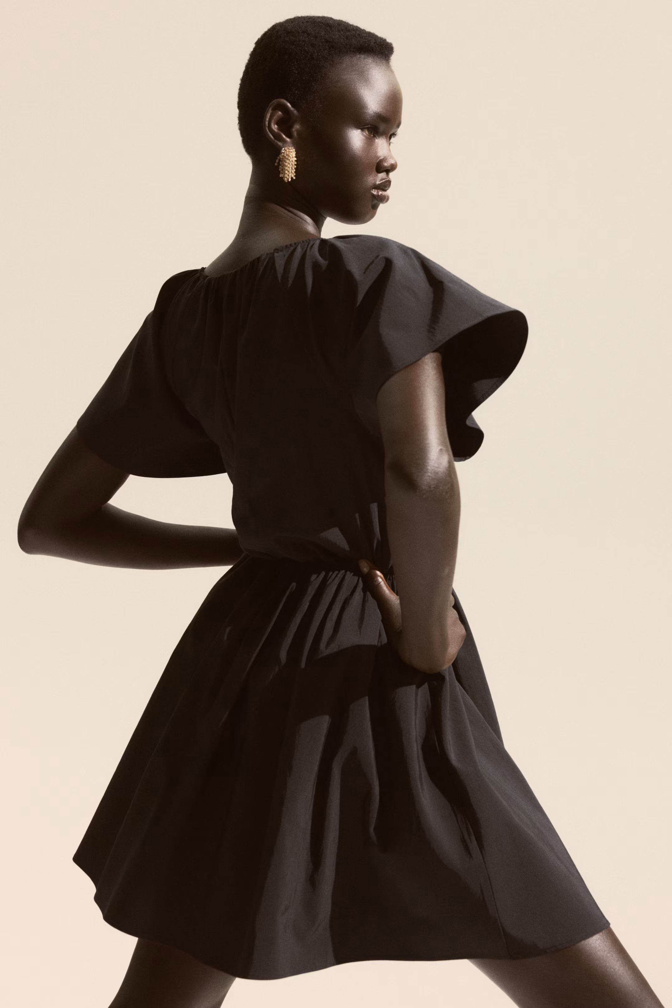 Model in a black flutter-sleeve mini dress