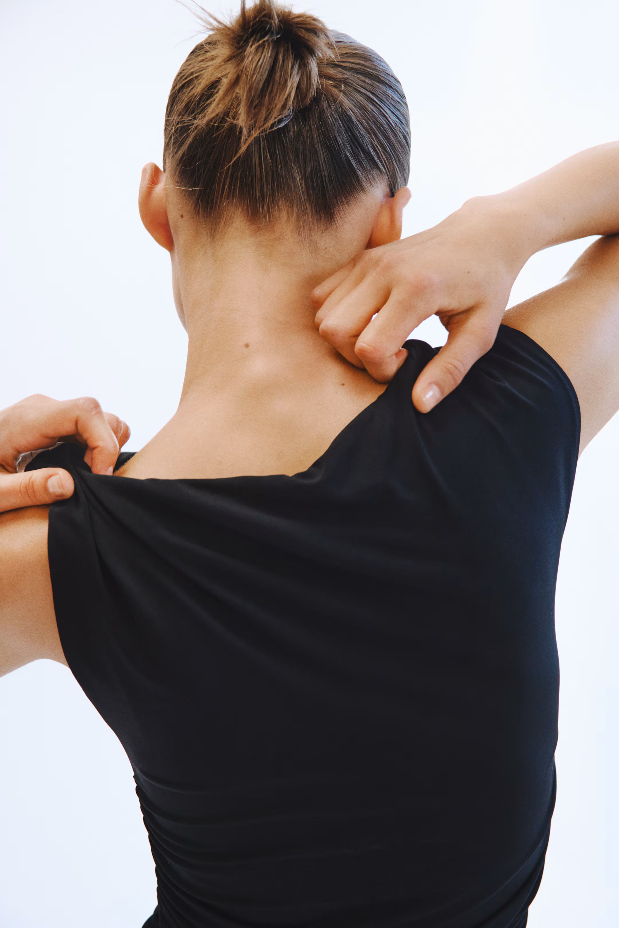 Model in a black ruched tank dress, viewed from behind