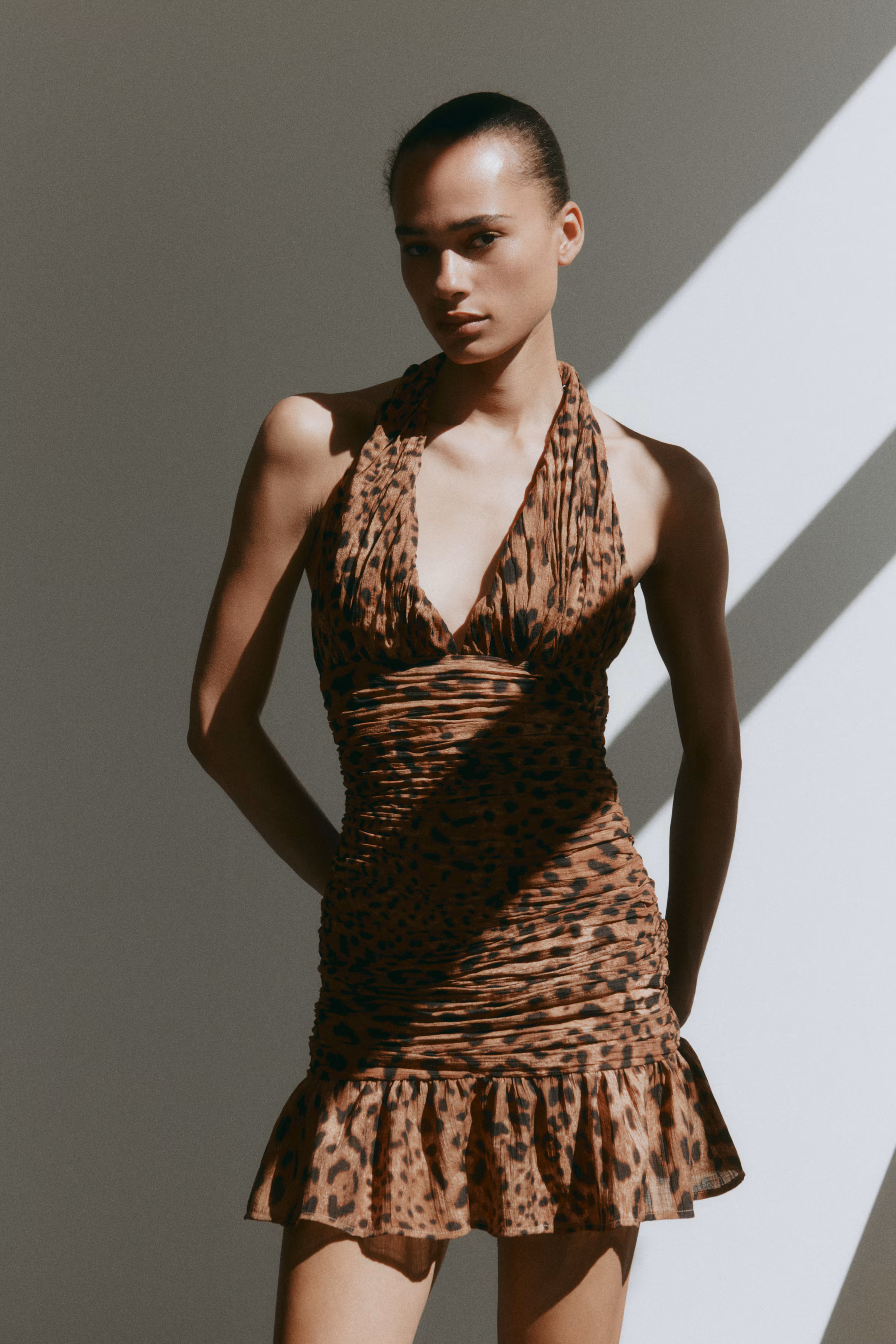 Model in a ruched leopard-print halter mini dress