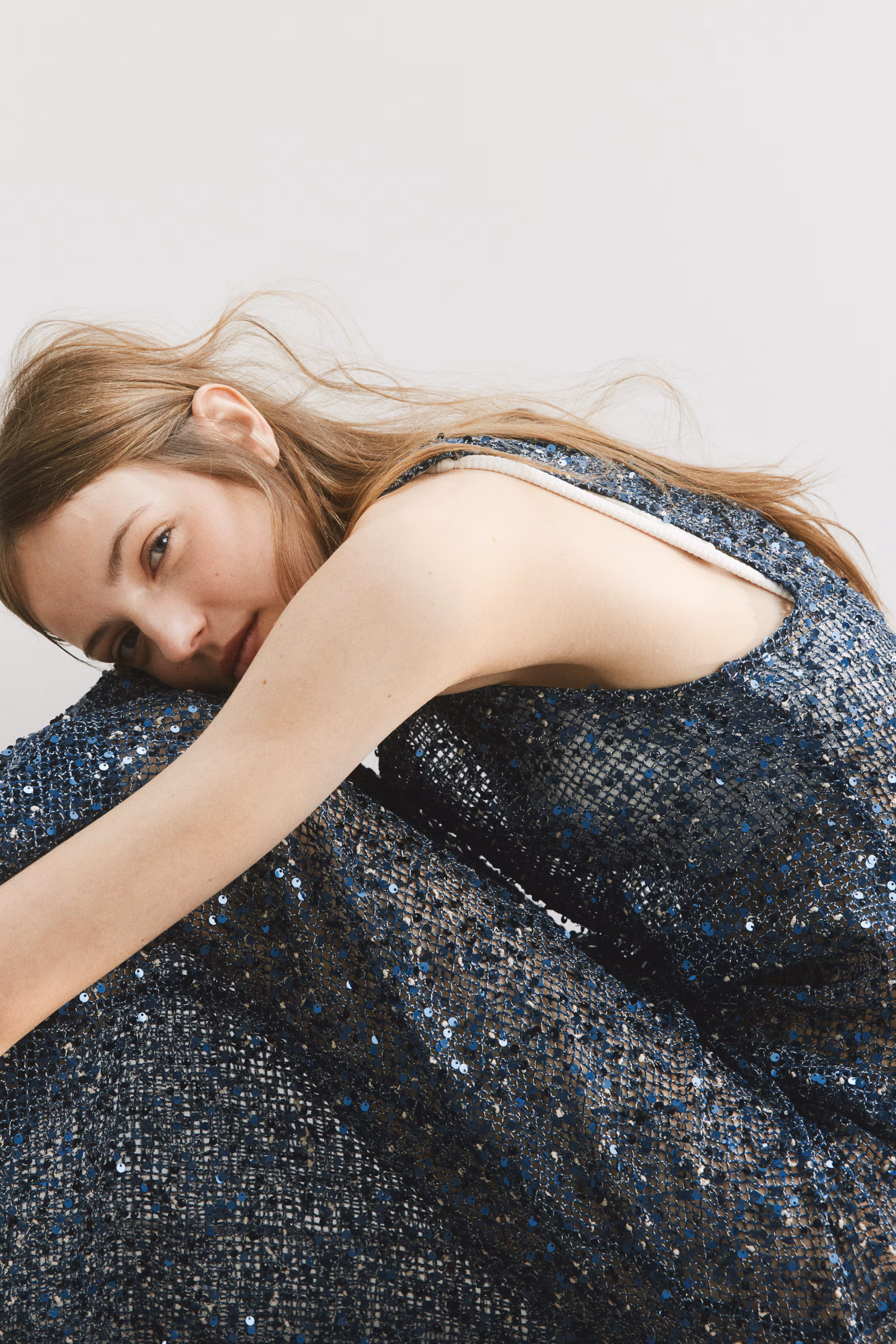 Model reclining in a textured grey knit dress